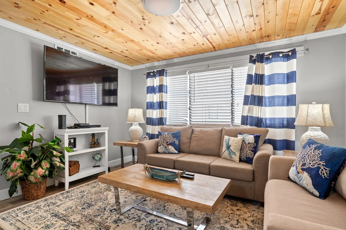 A thoughtfully arranged living area featuring a sofa, coffee table, TV, window treatments, and decorative lamps. The space feels open and inviting, designed for relaxation and easy movement.