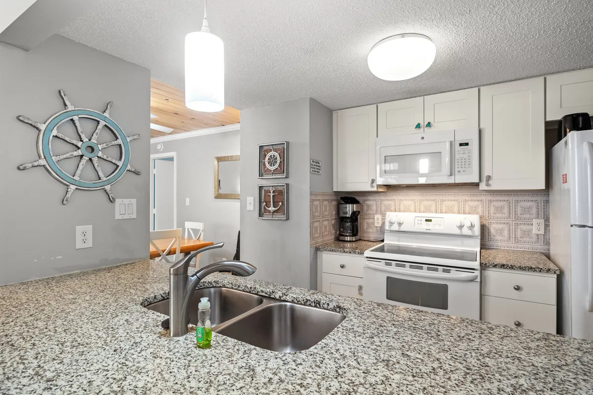 A stylish kitchen with granite countertops, modern appliances, and nautical-themed décor, designed for cooking and entertaining. The inviting layout encourages guests to prepare meals together or enjoy casual breakfasts.