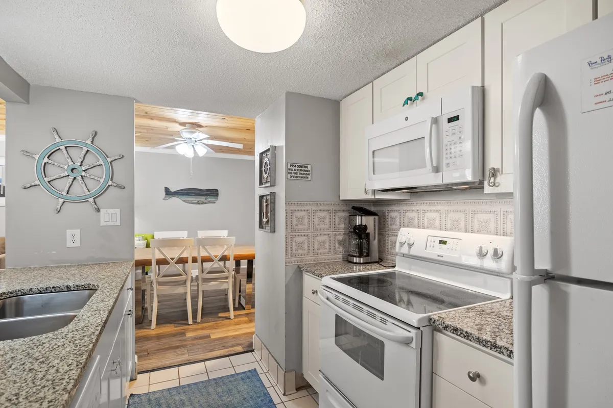 This image showcases the kitchen area, highlighting modern appliances, spacious countertops, and an open layout that flows into the dining area. Decorative wall art adds a welcoming touch, while the scene suggests ongoing cooking activity and a relaxed environment for shared meals and conversation.